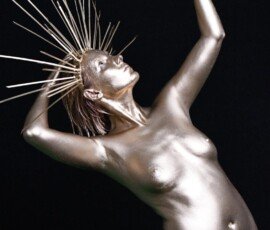 Glamorous metallic female sculpture with crown, posing elegantly against a black background. Shiny metallic female sculpture with crown, dramatic pose and dark background.