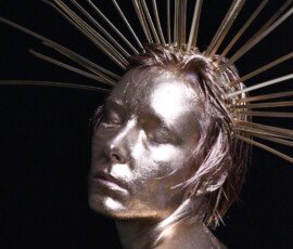 Elegant metallic female sculpture with radiant headpiece and smooth silver finish, highlighting modern art and creativity. Shiny metallic female sculpture with radiant headpiece and closed eyes.